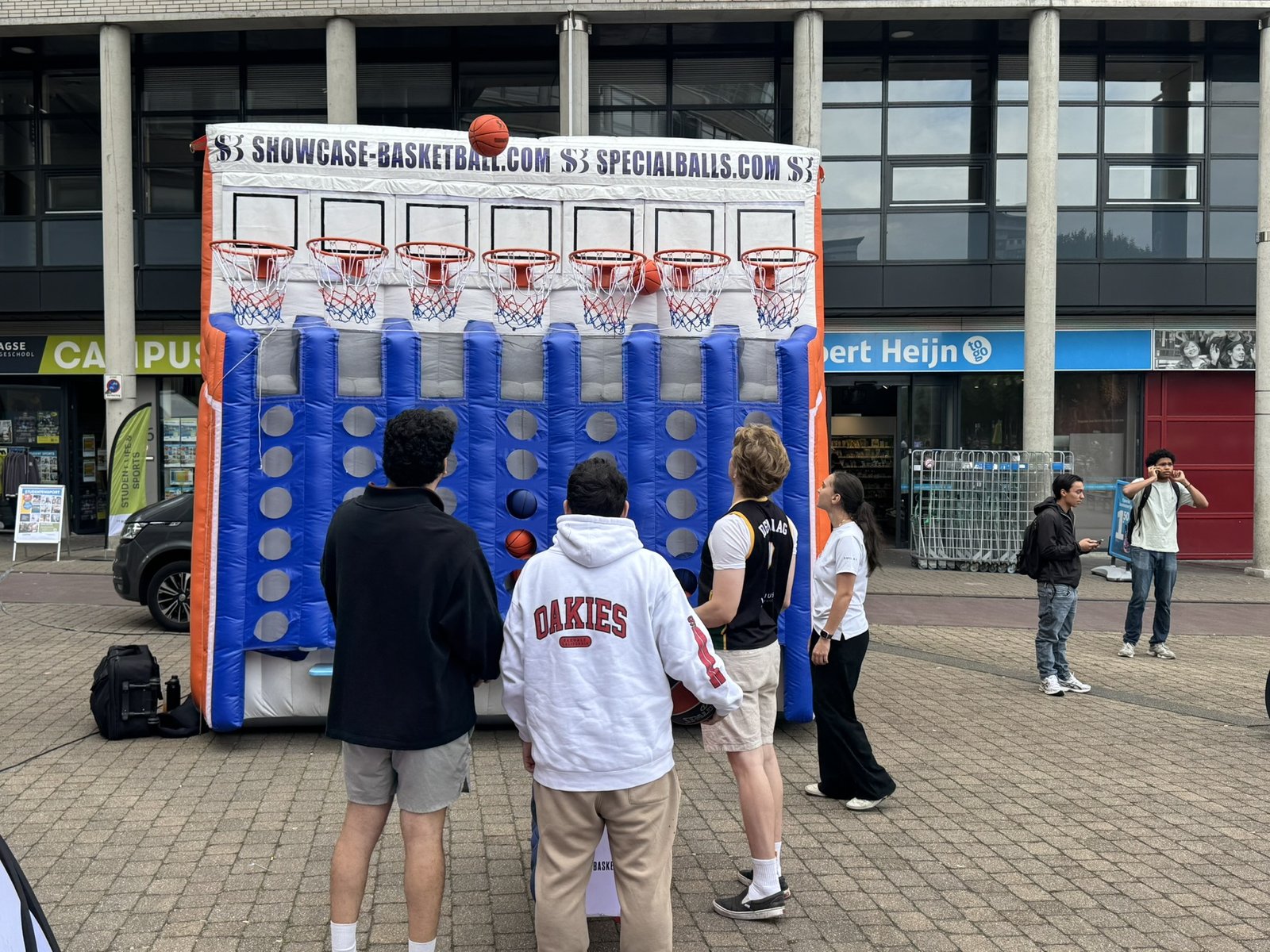 Drie studenten spelen samen levensgroot vier op een rij met een basketbal