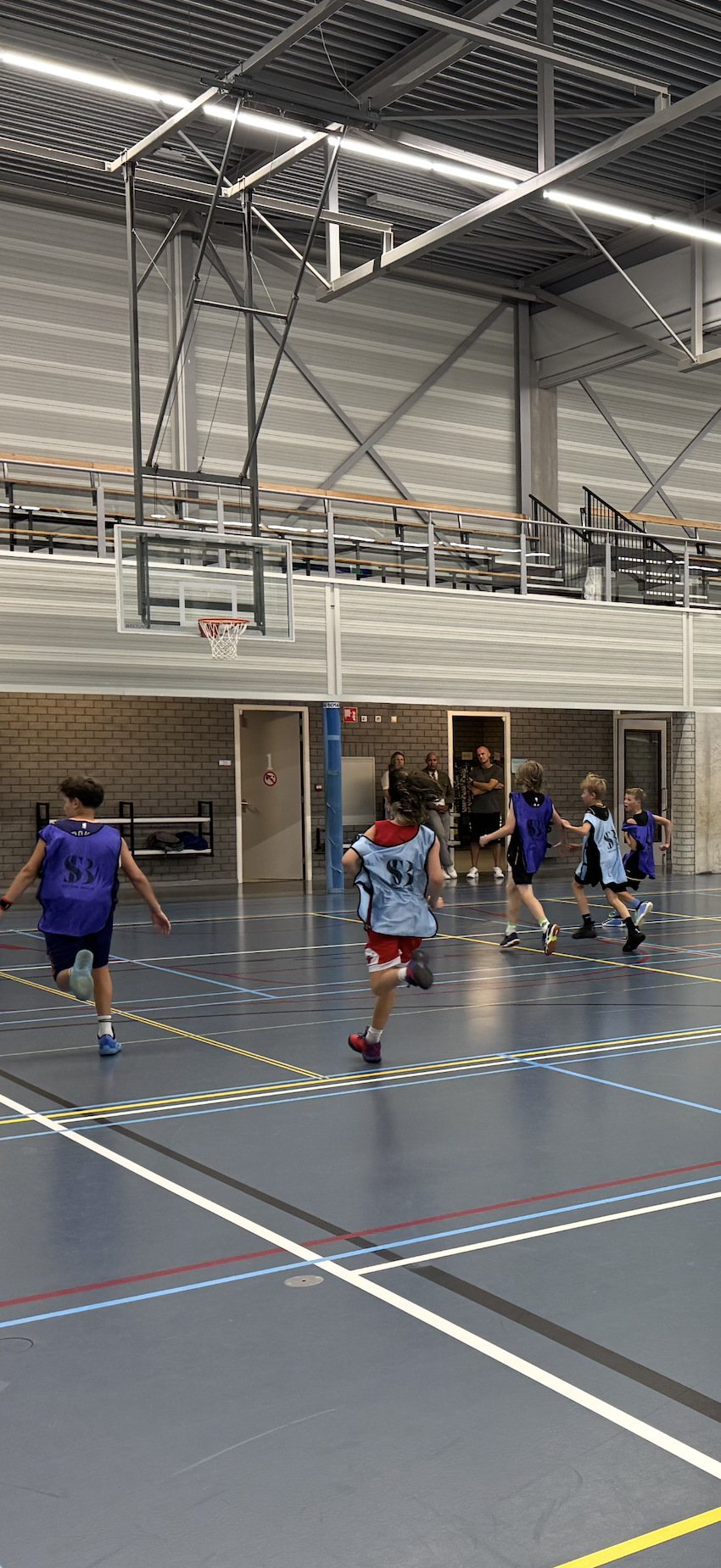 Spelers rennen door de zaal tijdens de warming-up bij BV Oegstgeest