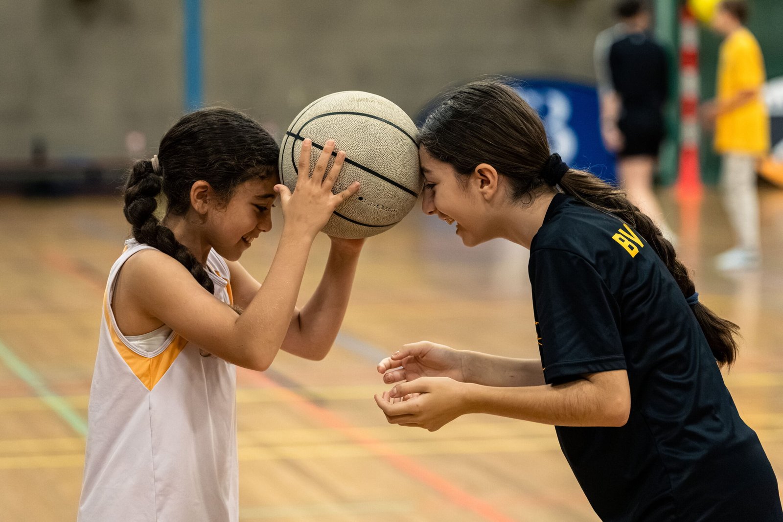 Twee jonge speelsters delen een moment met de bal tijdens de clinic