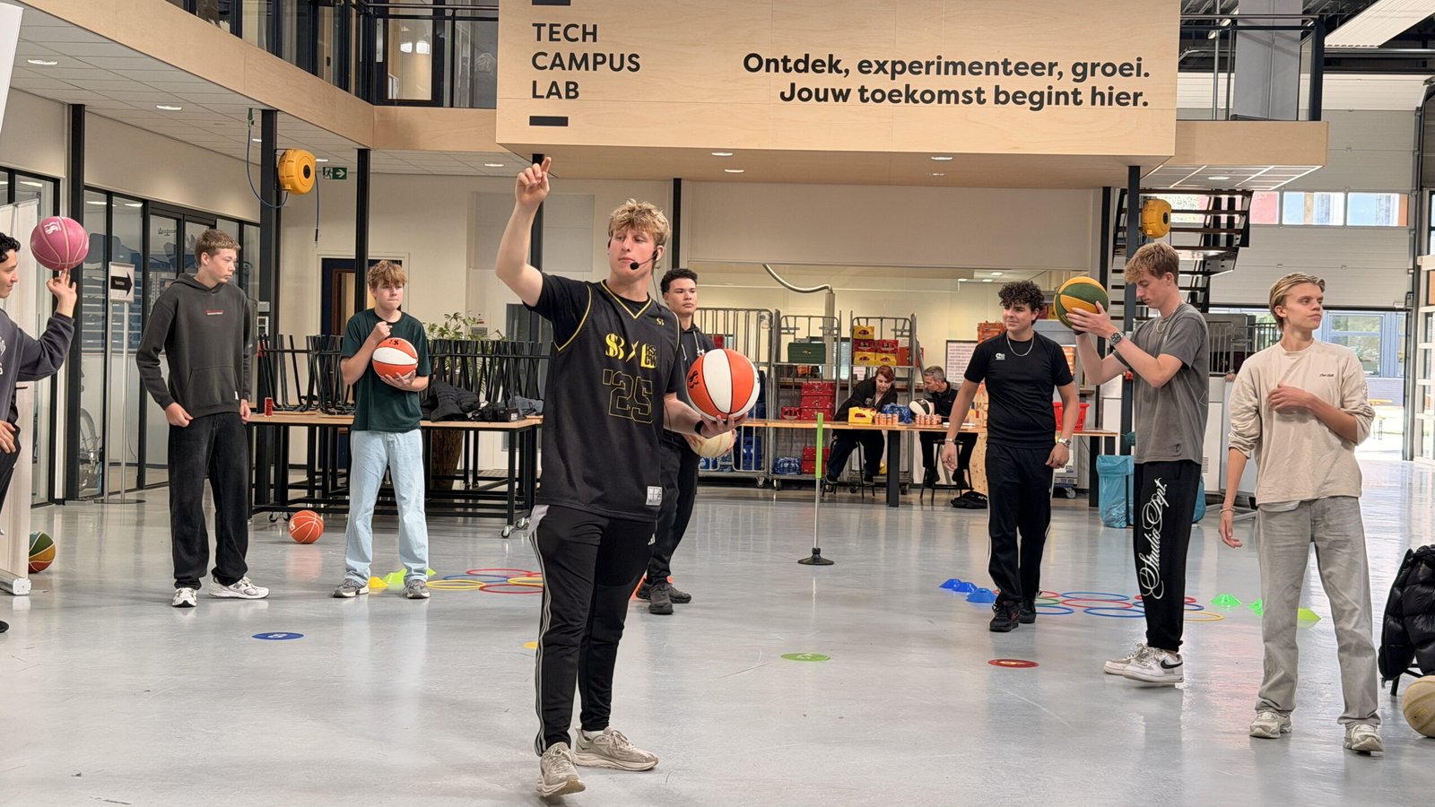 Teamlid laat een balvaardigheidstruc zien aan een groep leerlingen