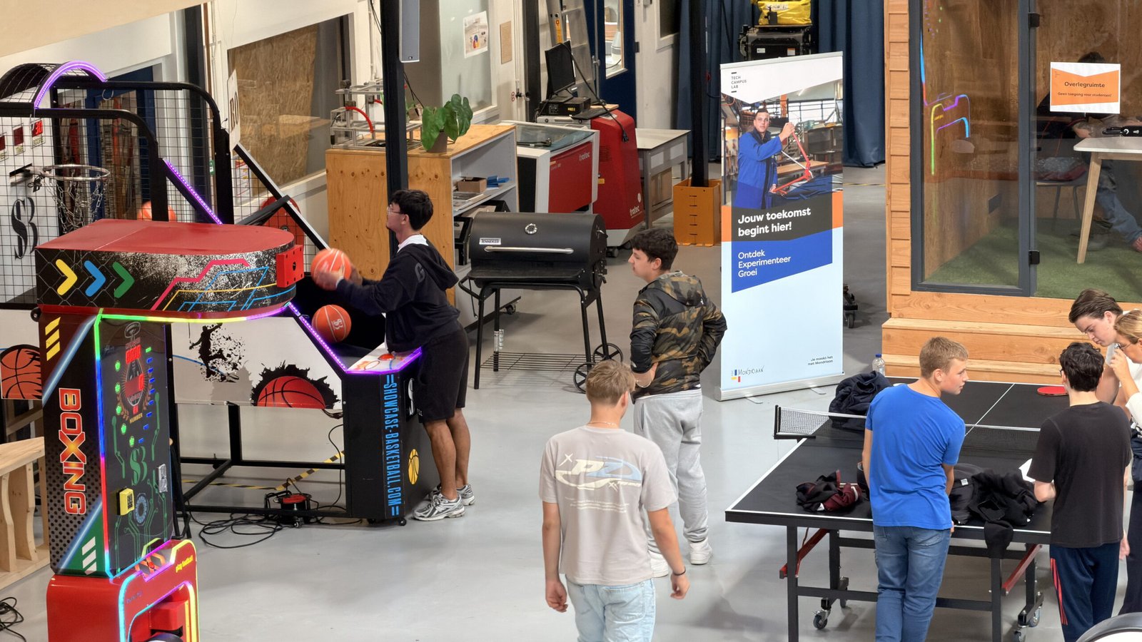 Leerlingen bij de boksmachine en de basketball-arcade in het atrium