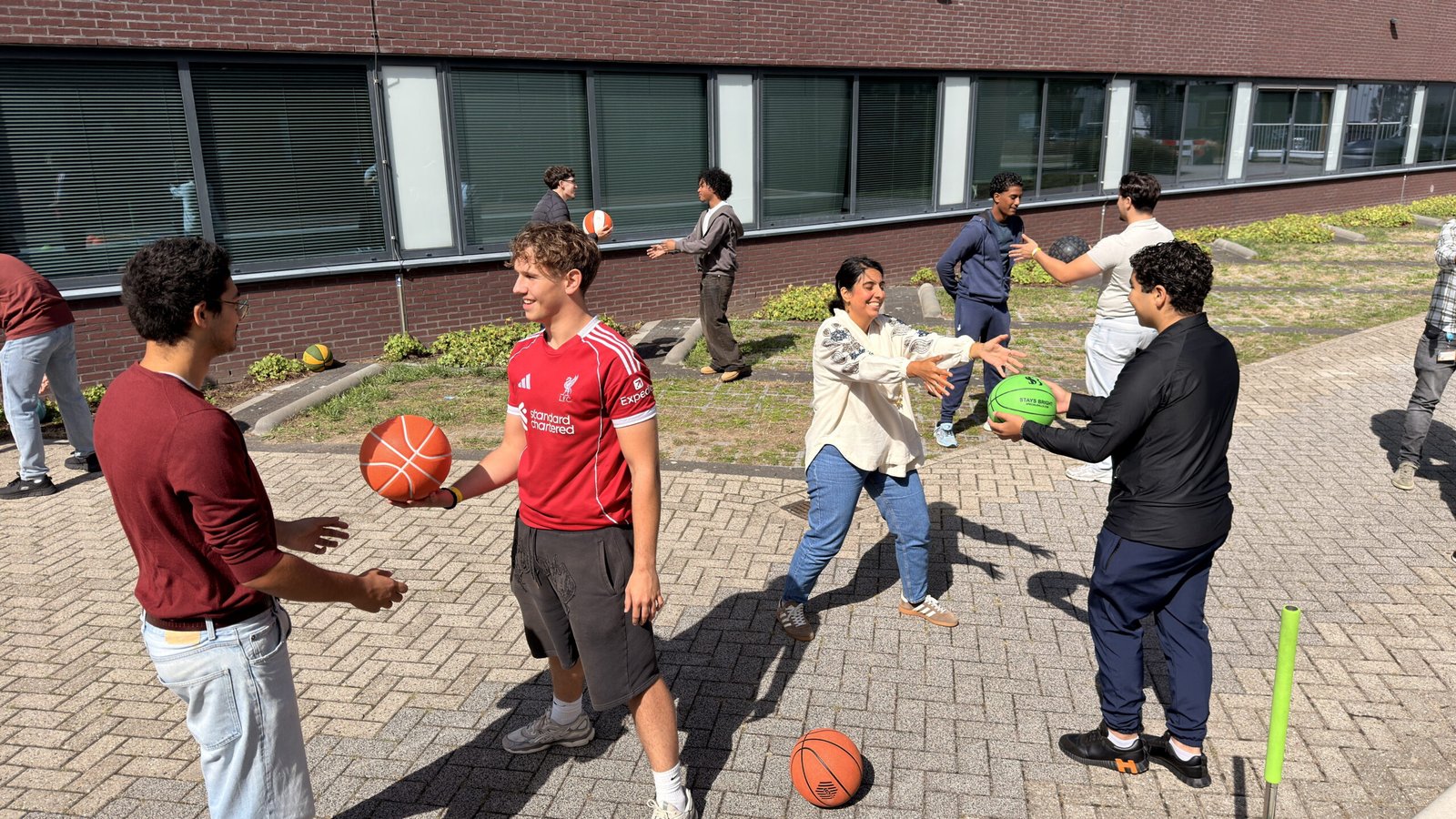 Groep leerlingen dribbelt buiten op het terrein van Mondriaan Tinwerf